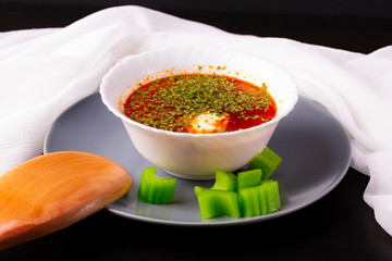 Russian and Ukrainian borsch with sour cream and parsley. Wooden spoon and celery. White towel beautiful towel.