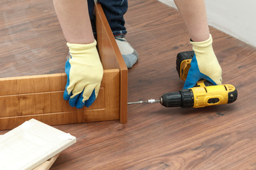 is the process of assembling furniture from chipboard. in the hands of a rechargeable screwdriver...
