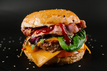 Tasty burger on the black background