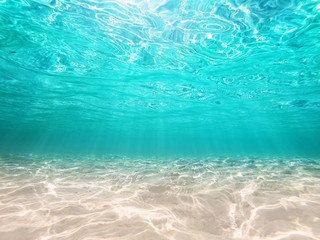 Fototapeta na wymiar underwater turquoise background deep blue sea and beautiful light rays with sandy floor