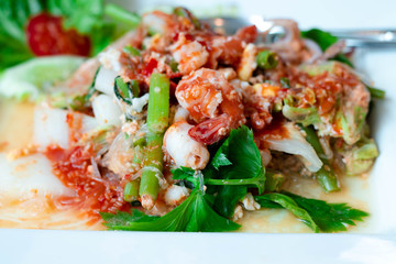 Dry suki Is a fast food popular of thai people dry suki this dish consists of with chinese cabbage shrimp, squid vermicelli and celery all in a white plate.
