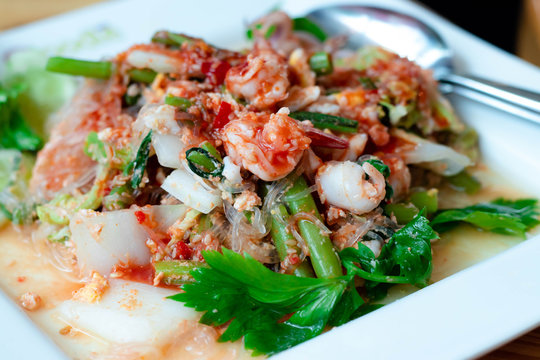 Dry suki Is a fast food popular of thai people dry suki this dish consists of with chinese cabbage shrimp, squid vermicelli and celery all in a white plate.