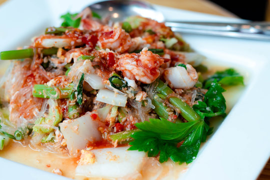 Dry suki Is a fast food popular of thai people dry suki this dish consists of with chinese cabbage shrimp, squid vermicelli and celery all in a white plate.