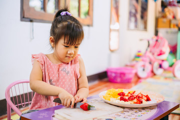 Cooking activity of kid making fruit salad ; healthy food.
