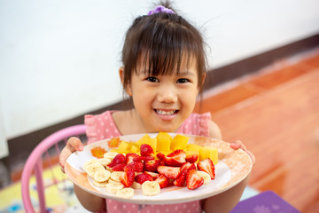 Cooking activity of kid making fruit salad ; healthy food.