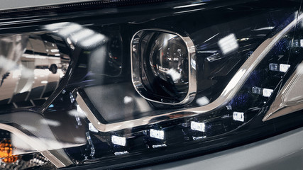 Closeup headlights of a modern car. Detail on the front light of a car. Modern and expensive car concept. The car is in the showroom