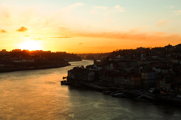 Dramatic sunset over the old city / old town of Porto with picturesque old buildings and boats as...