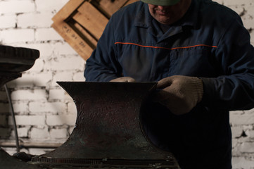 Blacksmith in workshop soldering metal object