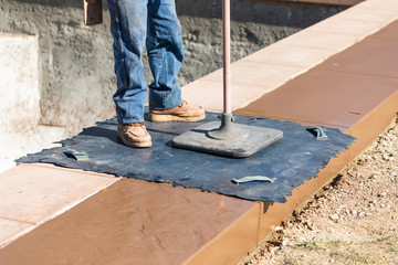 Construction Worker Applying Pressure to Texture Template On Wet Cement