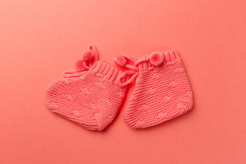 Baby booties on coral background. Top view. Flat lay. Copy space. Living Coral color of the Year 2019. Minimal style with colorful paper backdrop