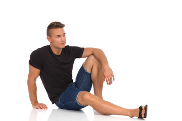Fototapeta premium Handsome Man Is Sitting Relaxed On A Floor And Looking Away