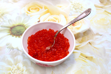 Red caviar in a bowl with a silver spoon
