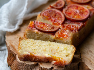 Homemade cake with blood oranges on on a wooden board and light gray background. Slice of cake. Piece of pie. Scandinavian style. Selective focus, copy space, close up