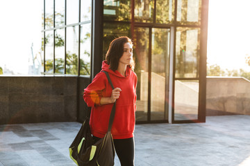 Smiling young sportswoman wearing a hoodie walking