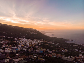 Fototapeta na wymiar sunset in Tenerife North with the cliff and a rock in the middle of the sea and a town. Picture by drone
