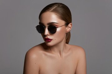 Portrait of young woman with sunglasses isolated over gray background