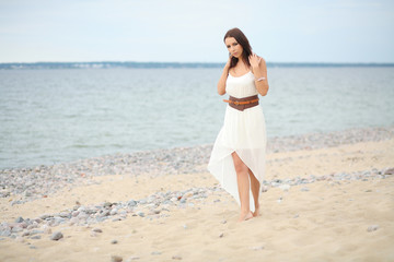 Fototapeta na wymiar Gorgeous dark-haired girl in dress on sandy beach