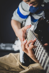 8 year old British Indian boy practices the electric guitar at home. 
