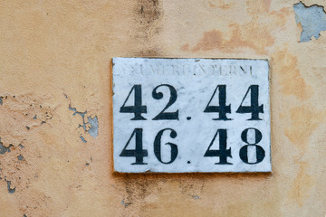 Close-up of a street sign with numbers on an orange wall in the old fishing village of Boccadasse, a famous neighborhood of Genoa, Liguria, Italy