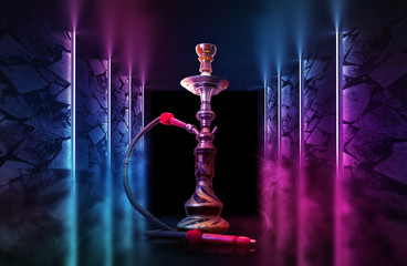 Hookah on the background of tropical leaves and a brick wall. Neon light, laser figures in smoke