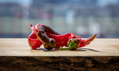 Two cayenne peppers twisted together on a wooden block