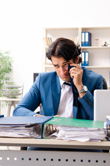 Young handsome busy employee sitting in office 