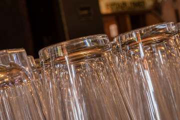 Closeup of clean and shiny pint glasses in a row tipping from right to left