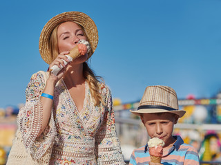 Mom and son enjoying their summer holidays and eating ice-cream in the Luna Park.