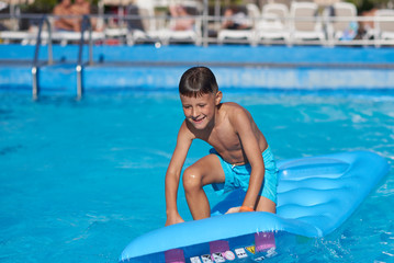 Smiling Caucasian boy having fun in swimming pool at resort on family vacation.