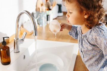 Little girl washing dishes in the kitchen at home