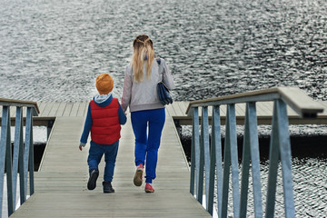 Cute boy and his mother are walking on the fresh air. They are enjoying the serenity around.