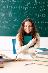 Young female math teacher in front of chalkboard  