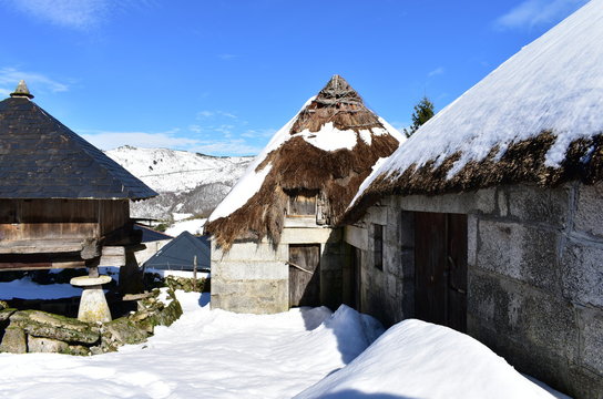 Snowy mountain village with ancient palloza houses made with stone and straw and galician granary (horreo). Piornedo, Lugo, Spain. 