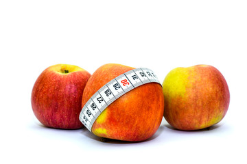 Photo isolated on white background apples and measuring tape. Healthy food for weight loss and keeping fit. Tape for measuring the waist and apples.