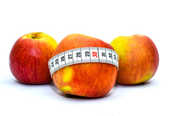 Photo isolated on white background apples and measuring tape. Healthy food for weight loss and keeping fit. Tape for measuring the waist and apples.