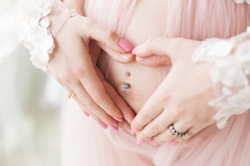 hands men and women on pregnant belly. hands folded fingers little heart on his stomach. pregnant belly