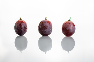 Three red wet grapes isolated