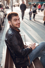 Brunette man with beard smiling and writing in notebook