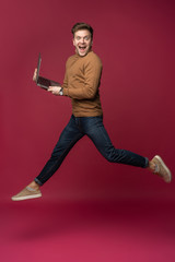 Full length portrait of a cheerful young man wearing casual clothes isolated over pink background,...