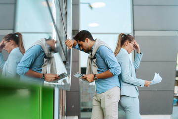 Fototapeta premium Desperate two businesspersons failing at work. They standing outdoors in front of business center and holding paperwork and tablet.