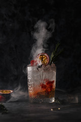 Cocktail in a bar on a dark background in smoke and steam. Alcoholic shot with fruit and ice. Food...