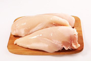 Raw chicken breasts and spices on wooden cutting board, close up