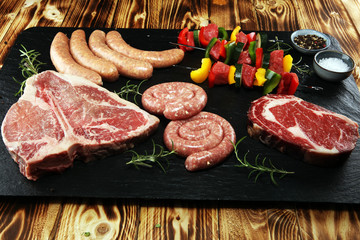 Assorted delicious raw meat with vegetable on a barbecue with t-bone steak, sausages and meat Skewers.