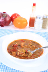 Selective Focus on bowl of gumbo Surrounded by spices and ingredients.