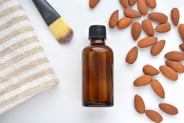 Organic cosmetic almond oil in brown bottle for skin, hair, nail treatment, flat lay composition with linen towel