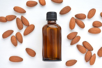 Natural almond oil in brown bottle for cosmetics and nuts, close up, top view.