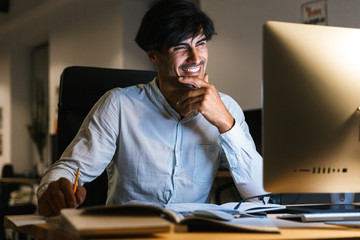 Smiling young man working at the office late at night