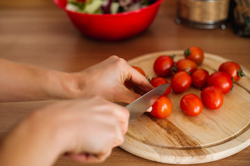 close up of female hand cutting tomato on cutting board with sharp knife