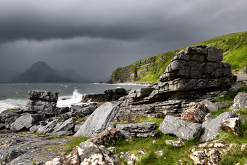 Cliffs and shore north of Elgol Port na Cullaidh with Red Cuillin Mountains under dark clouds on Loch Scavaig Isle of Skye Scotland UK