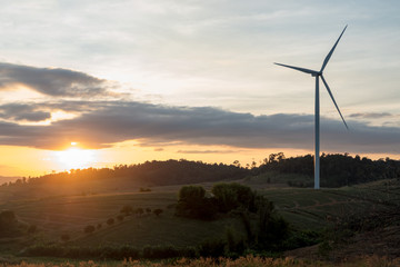 Obraz premium Silhouette of wind turbines on the mountain at sunset.